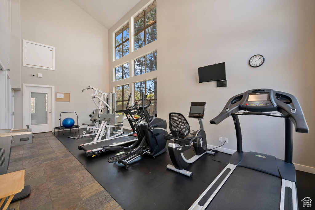 Exercise room featuring dark tile floors and high vaulted ceiling