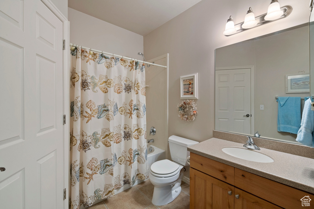 Full bathroom with tile floors, toilet, vanity, and shower / tub combo with curtain