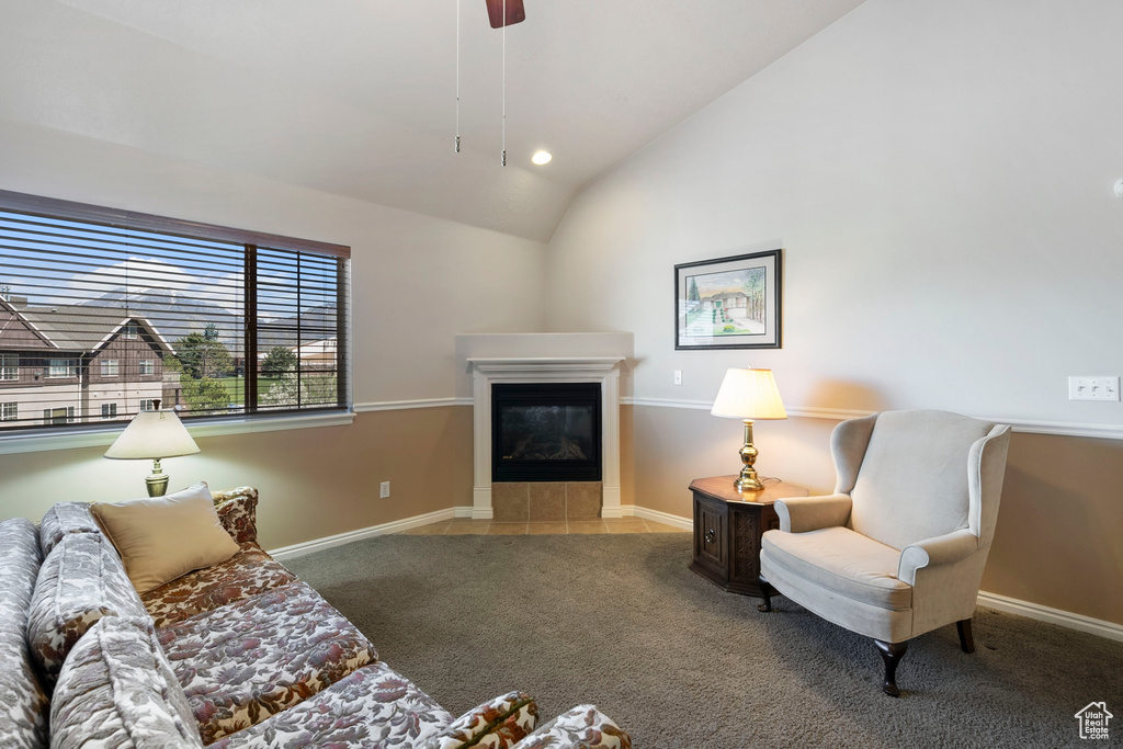 Living room featuring a tile fireplace, carpet flooring, and vaulted ceiling