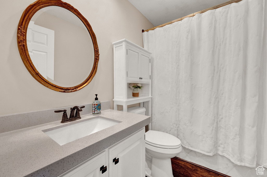 Bathroom with vanity with extensive cabinet space, toilet, and hardwood / wood-style floors