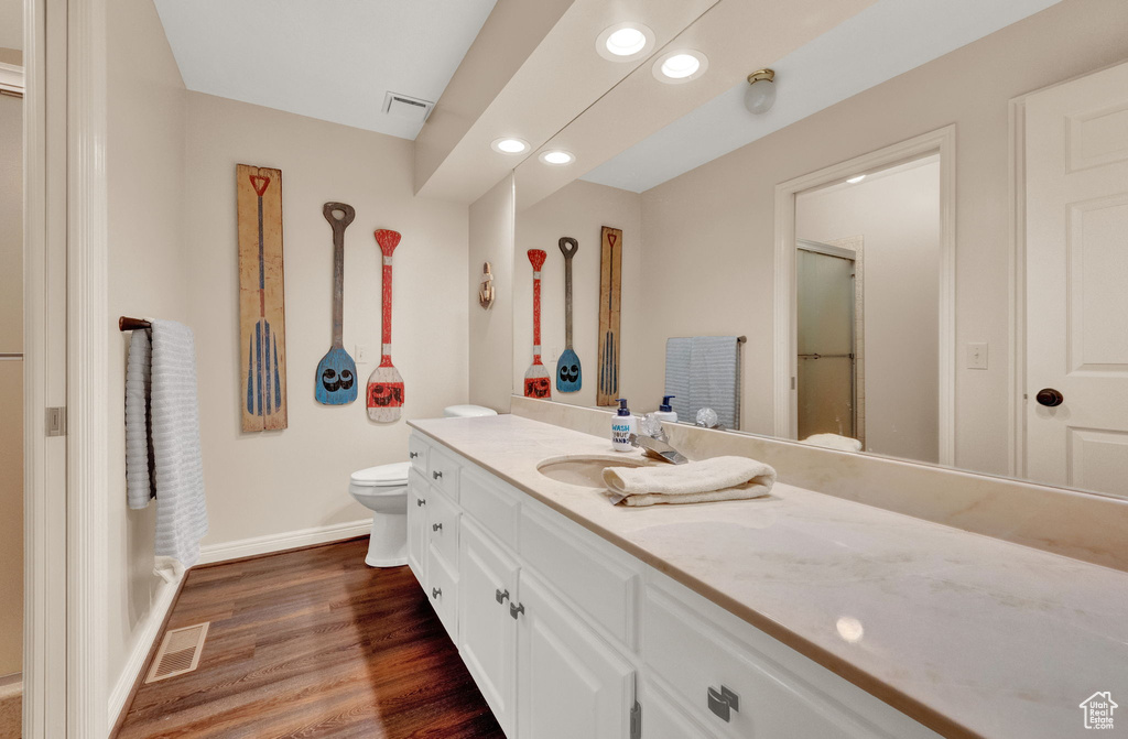 Bathroom with vanity with extensive cabinet space, hardwood / wood-style flooring, and toilet
