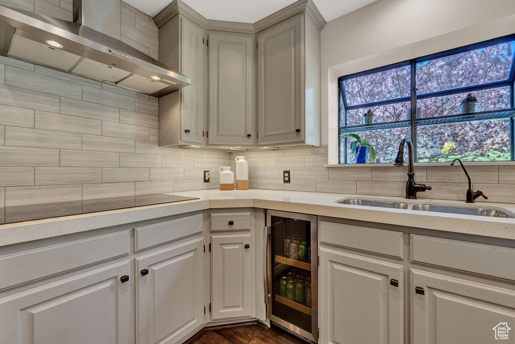 Kitchen with beverage cooler, tasteful backsplash, wall chimney exhaust hood, and a healthy amount of sunlight