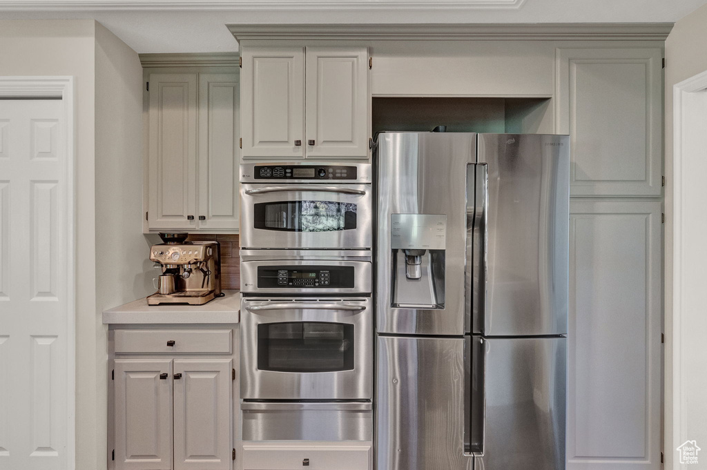 Kitchen with backsplash, appliances with stainless steel finishes, and white cabinets