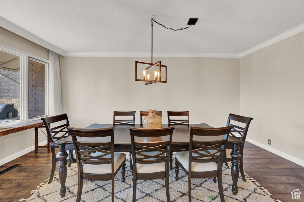 Dining space featuring a chandelier, crown molding, and dark wood-type flooring