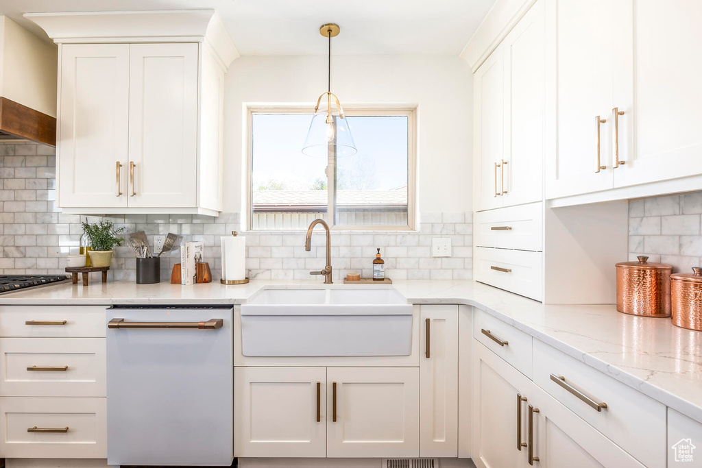 Kitchen featuring backsplash, wall chimney range hood, white cabinetry, and dishwasher