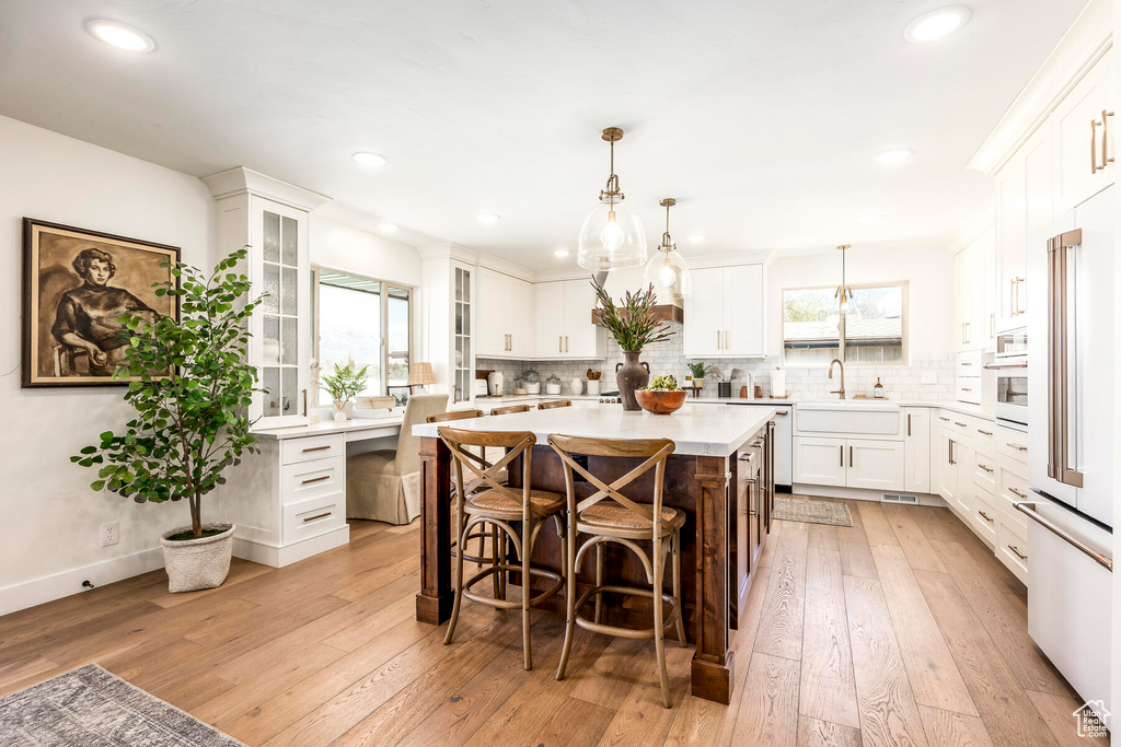 Kitchen featuring light hardwood / wood-style flooring, sink, a center island, and white cabinets