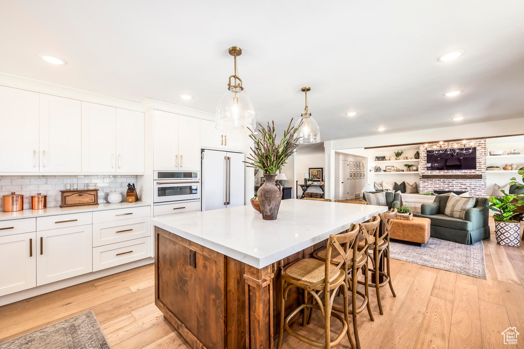 Kitchen with high end white fridge, light hardwood / wood-style flooring, white cabinetry, and oven