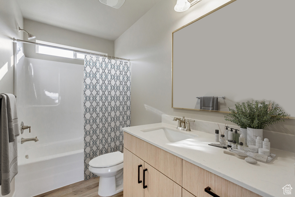 Full bathroom with shower / tub combo, toilet, large vanity, and hardwood / wood-style flooring