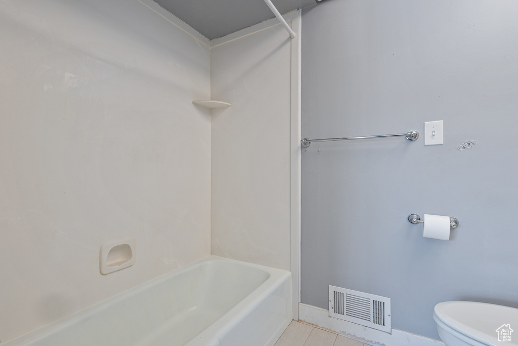 Bathroom featuring bathtub / shower combination, toilet, and tile flooring