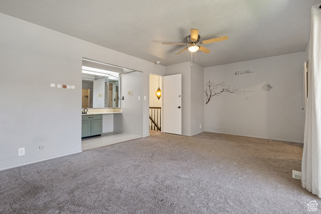 Unfurnished room featuring light colored carpet, ceiling fan, and sink