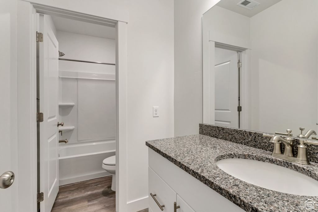Full bathroom with shower / bathing tub combination, oversized vanity, hardwood / wood-style floors, and toilet