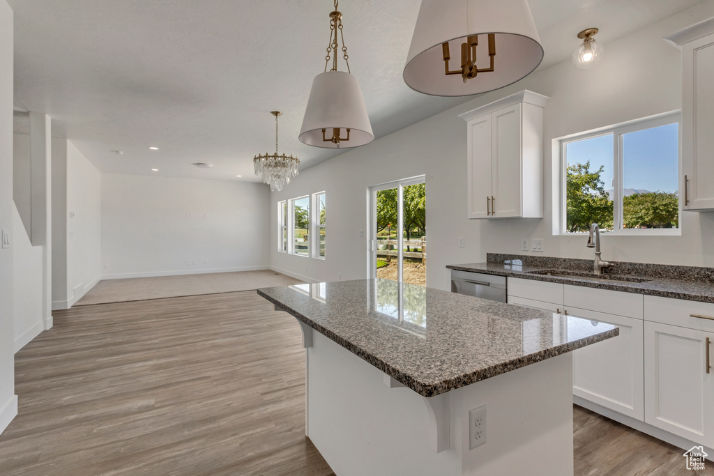 Kitchen featuring a center island, light hardwood / wood-style floors, white cabinets, and pendant lighting