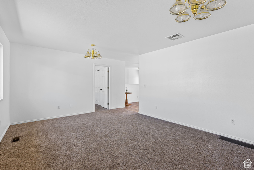 Empty room with dark carpet and an inviting chandelier