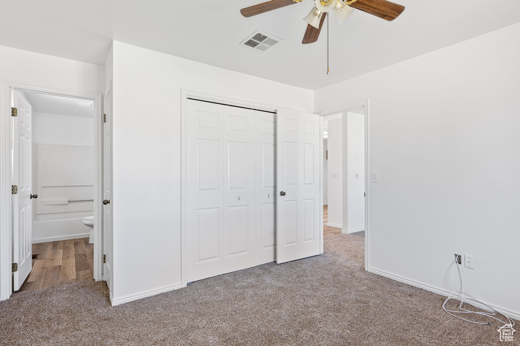 Unfurnished bedroom with connected bathroom, a closet, ceiling fan, and dark carpet