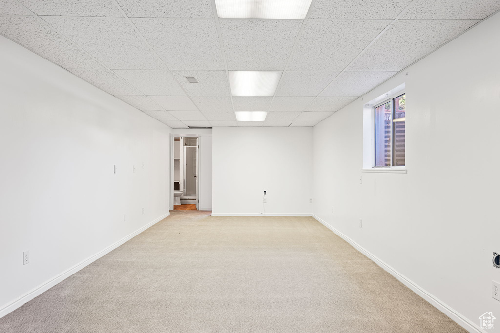 Basement featuring light carpet and a paneled ceiling