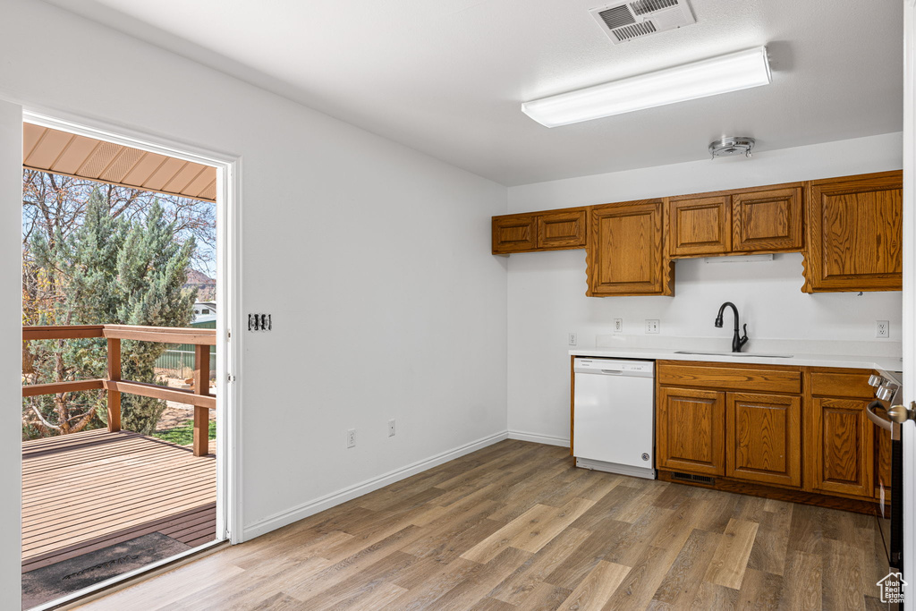 Kitchen with light hardwood / wood-style flooring, sink, white dishwasher, and stove