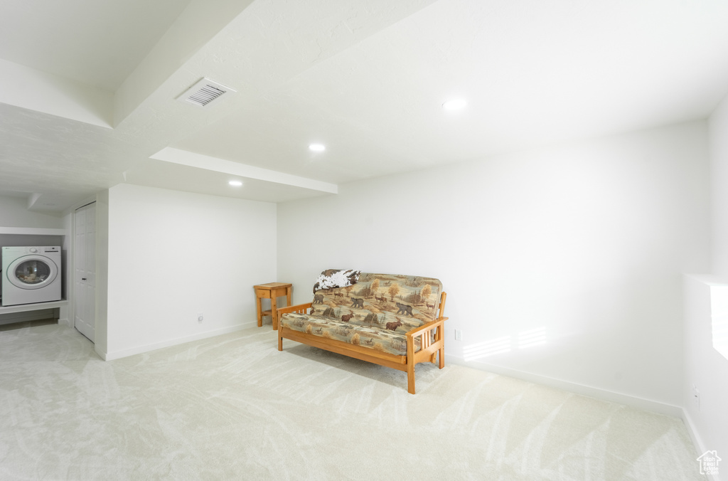 Living area featuring light colored carpet and washer / dryer