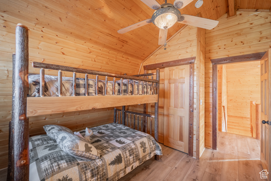 Bedroom featuring wood walls, ceiling fan, light hardwood / wood-style floors, beam ceiling, and wood ceiling