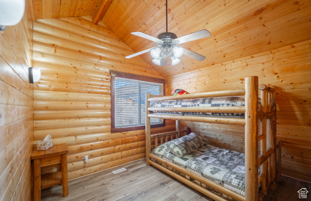 Bedroom with log walls, wooden ceiling, light hardwood / wood-style floors, and lofted ceiling with beams