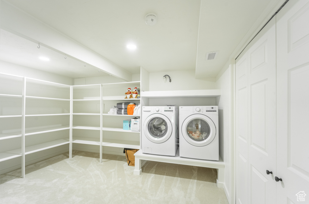 Clothes washing area with light carpet and washing machine and dryer