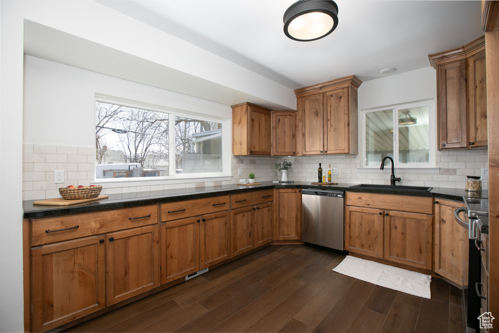 Kitchen with appliances with stainless steel finishes, sink, dark wood-type flooring, and backsplash