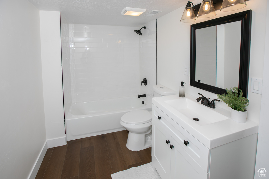 Full bathroom featuring toilet, wood-type flooring, a textured ceiling, vanity, and bathing tub / shower combination