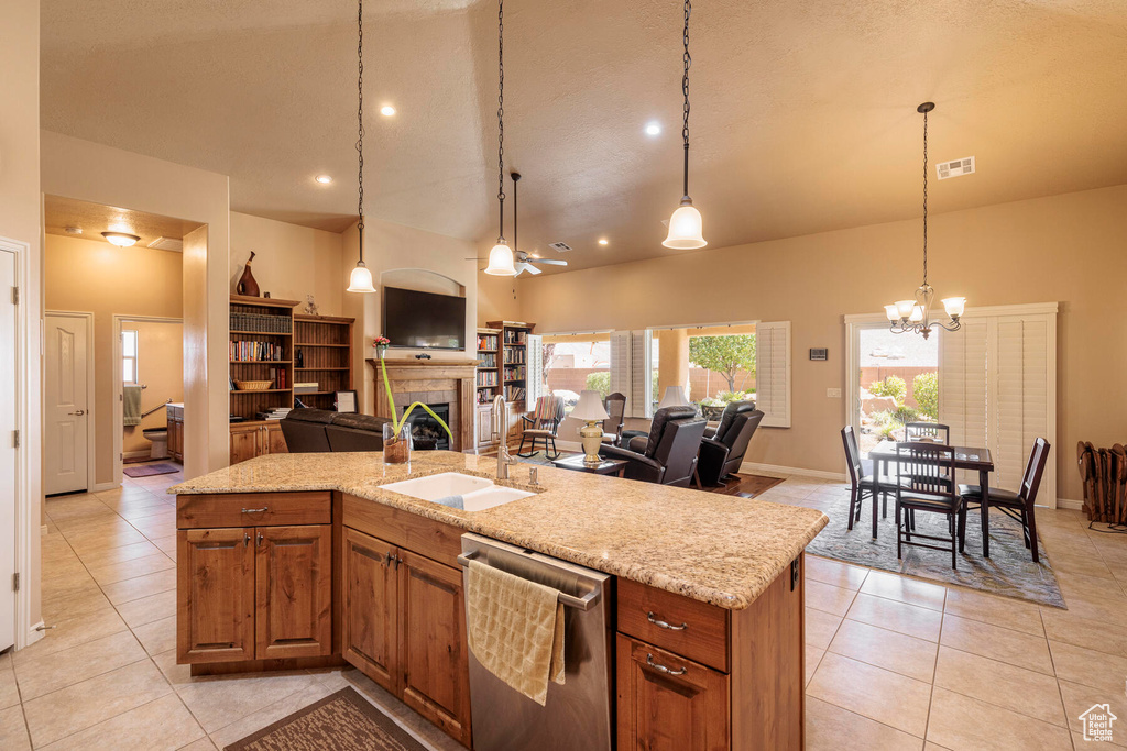 Kitchen featuring dishwasher, a tile fireplace, sink, pendant lighting, and light tile floors