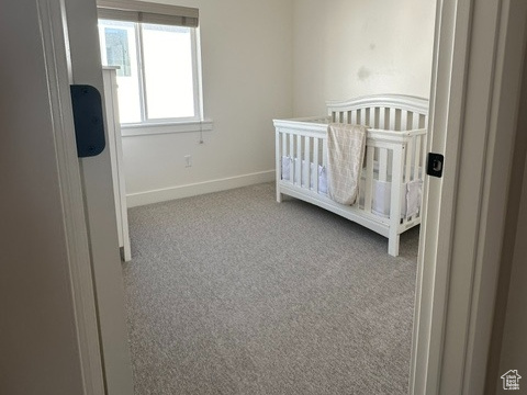 Unfurnished bedroom featuring light carpet and a crib