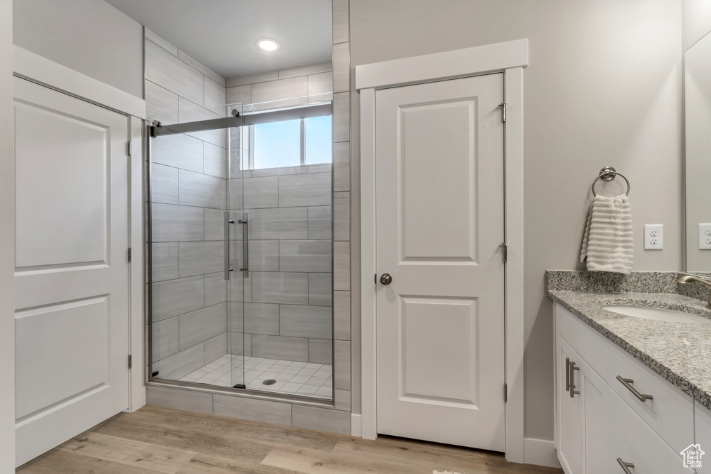 Bathroom with oversized vanity, hardwood / wood-style flooring, and a shower with shower door