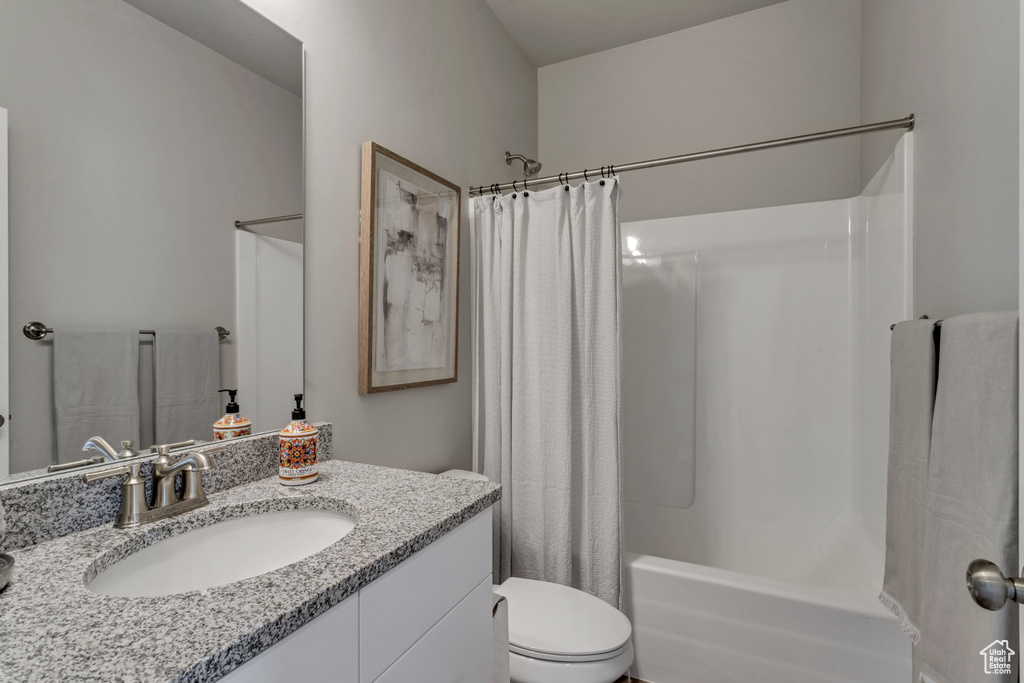 Full bathroom with oversized vanity, shower / bath combination with curtain, and toilet