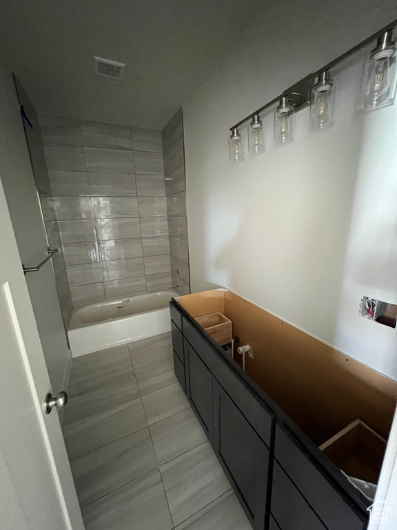 Bathroom with tiled shower / bath combo and tile floors