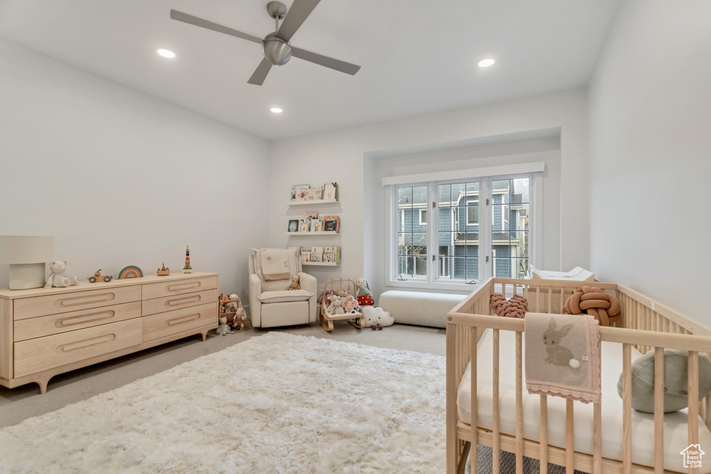 Bedroom with ceiling fan, a crib, and carpet