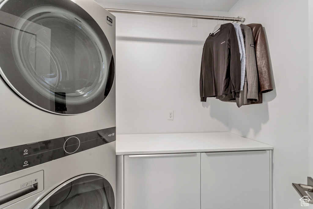 Laundry area with cabinets and stacked washer and clothes dryer