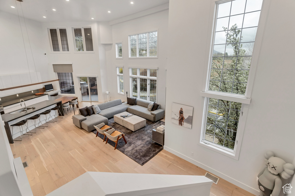 Living room with a towering ceiling, light wood-type flooring, and a wealth of natural light