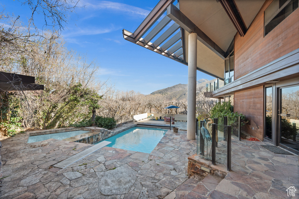 View of pool with a mountain view, an outdoor hot tub, and a patio