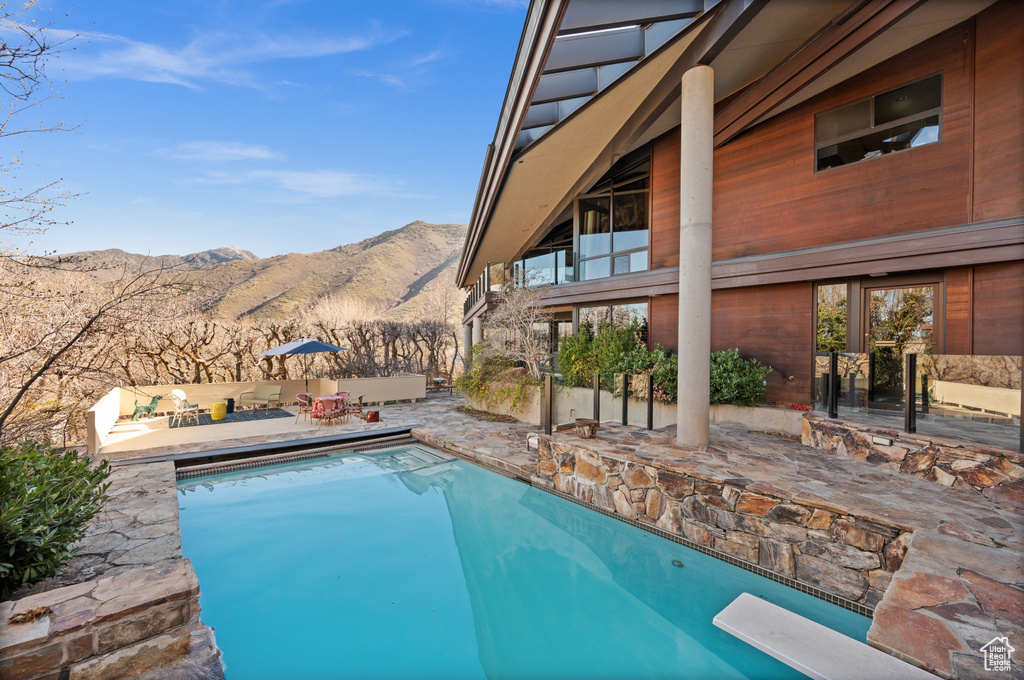 View of pool with a mountain view, a diving board, and a patio
