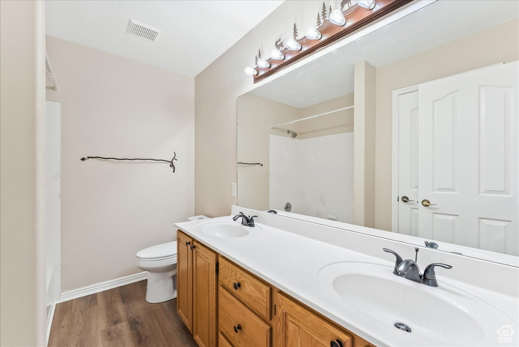 Full bathroom featuring bathtub / shower combination, double vanity, hardwood / wood-style floors, and toilet