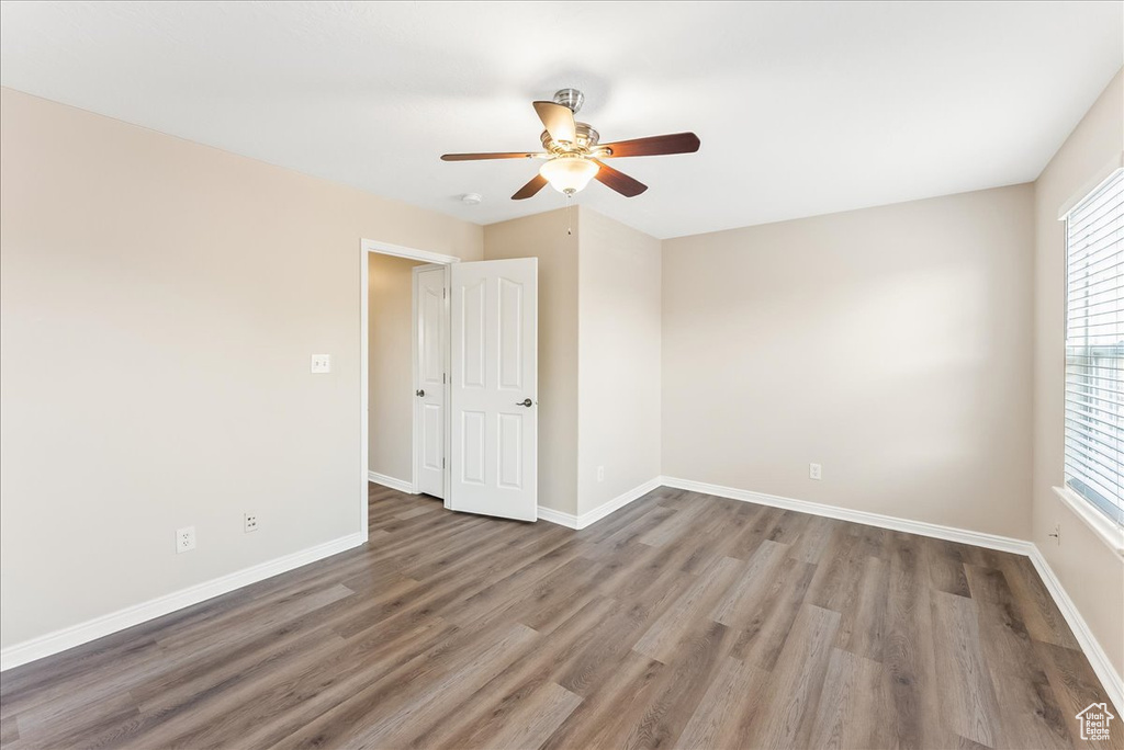 Unfurnished room with ceiling fan, plenty of natural light, and dark wood-type flooring