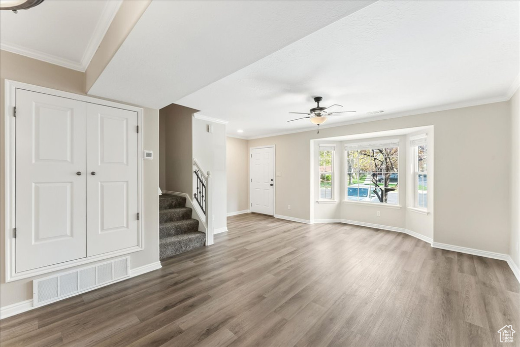 Interior space with ornamental molding, dark hardwood / wood-style flooring, and ceiling fan