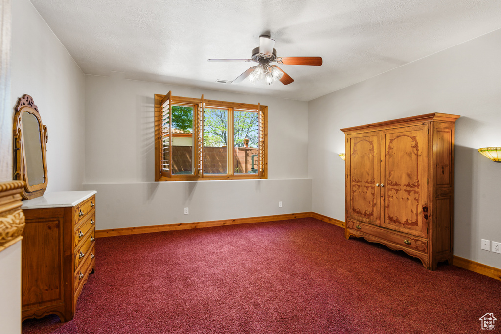 Unfurnished bedroom featuring ceiling fan and dark colored carpet