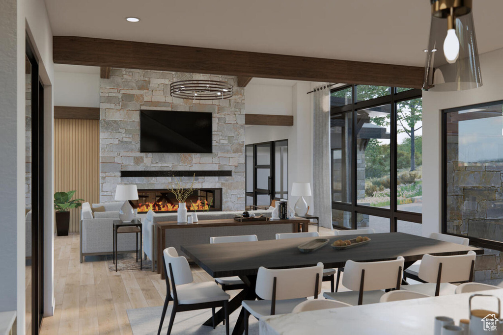 Dining room with a stone fireplace, beam ceiling, and light wood-type flooring