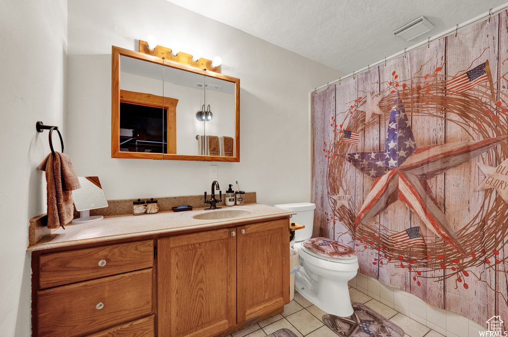 Bathroom featuring a textured ceiling, vanity, toilet, and tile floors