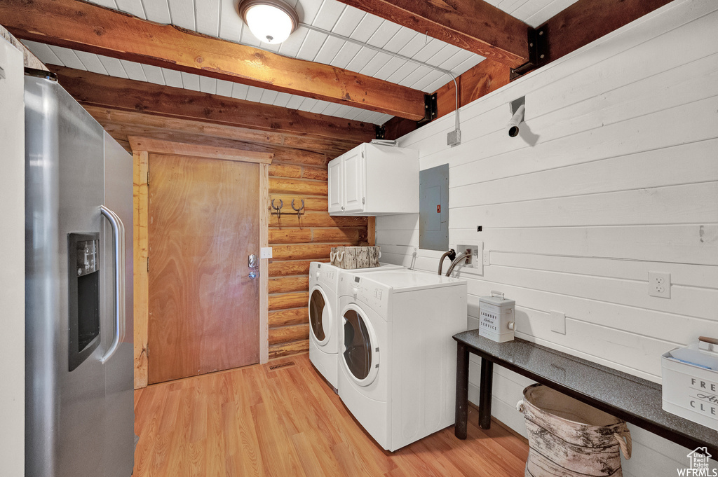 Clothes washing area featuring hookup for a washing machine, washing machine and clothes dryer, light hardwood / wood-style flooring, cabinets, and rustic walls