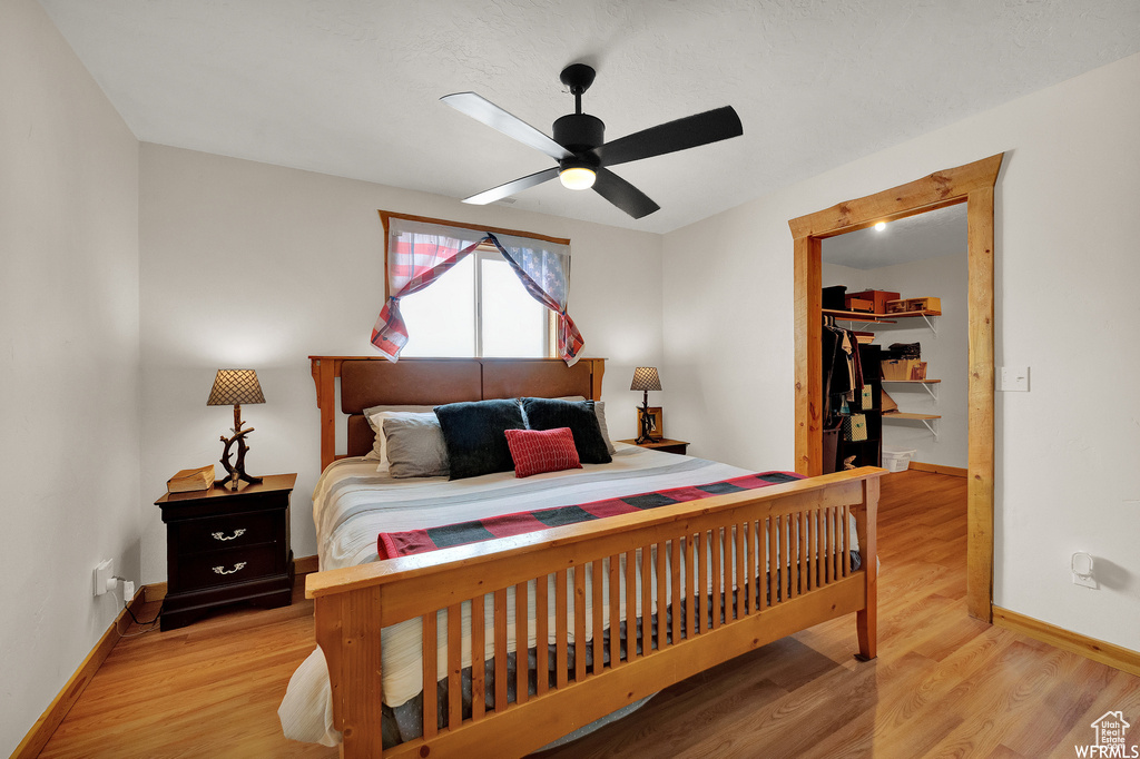 Bedroom featuring ceiling fan, a walk in closet, light hardwood / wood-style floors, and a closet