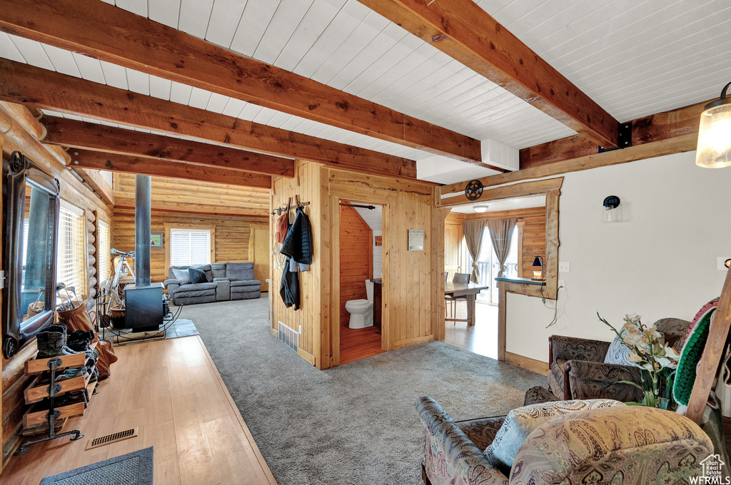 Living room with a wood stove, light hardwood / wood-style flooring, and beam ceiling