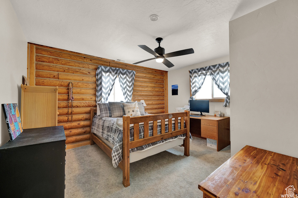 Bedroom featuring ceiling fan, light carpet, and rustic walls