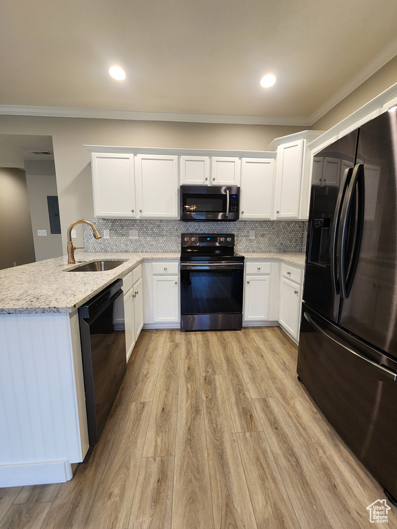 Kitchen featuring tasteful backsplash, black appliances, sink, and light wood-type flooring