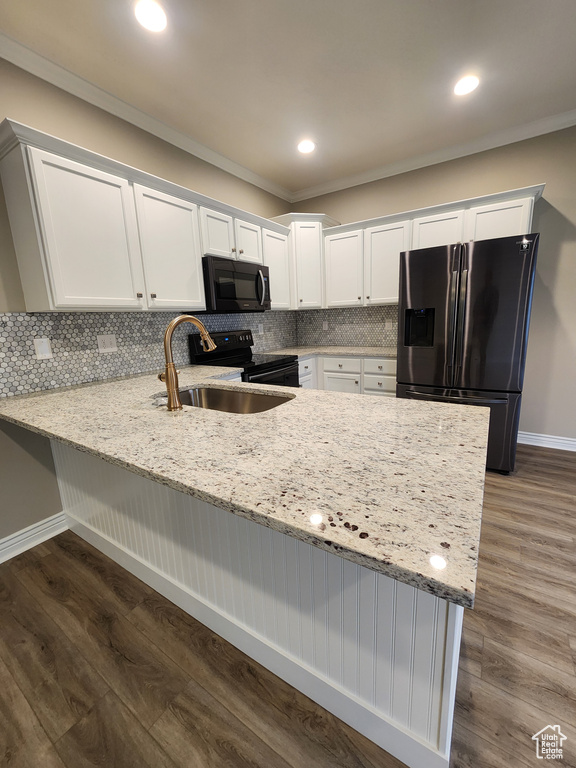 Kitchen featuring dark wood-type flooring, white cabinetry, black appliances, backsplash, and kitchen peninsula