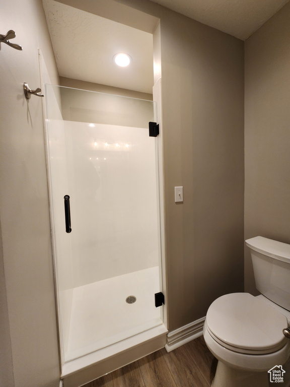 Bathroom with hardwood / wood-style flooring, toilet, and walk in shower
