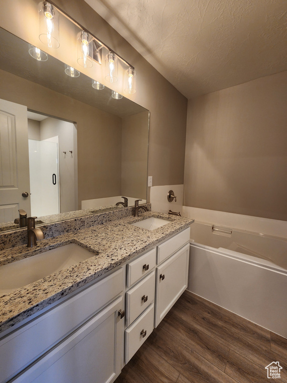 Bathroom with hardwood / wood-style floors, double vanity, and a bath to relax in